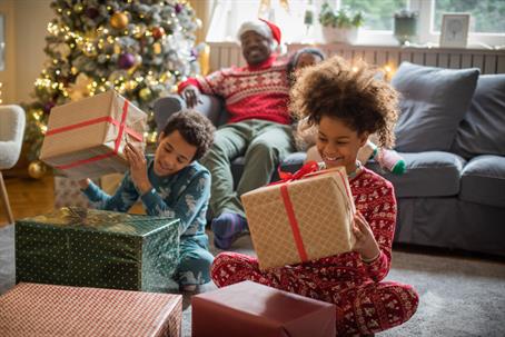 children opening Christmas presents while parent watches