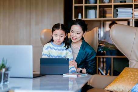 mother and daughter looking at a tablet and a laptop